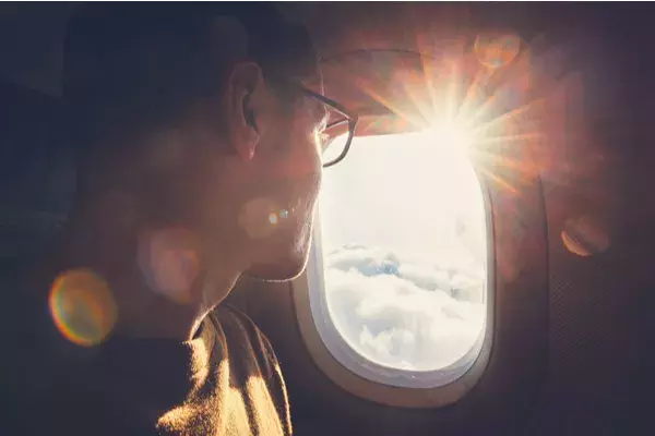 Smiling man looking out airplane window